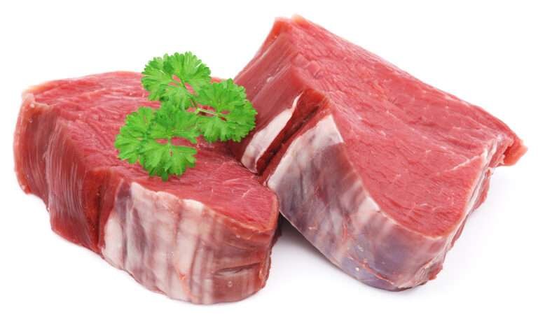 Two raw beef steaks, garnished with parsley. Meat.